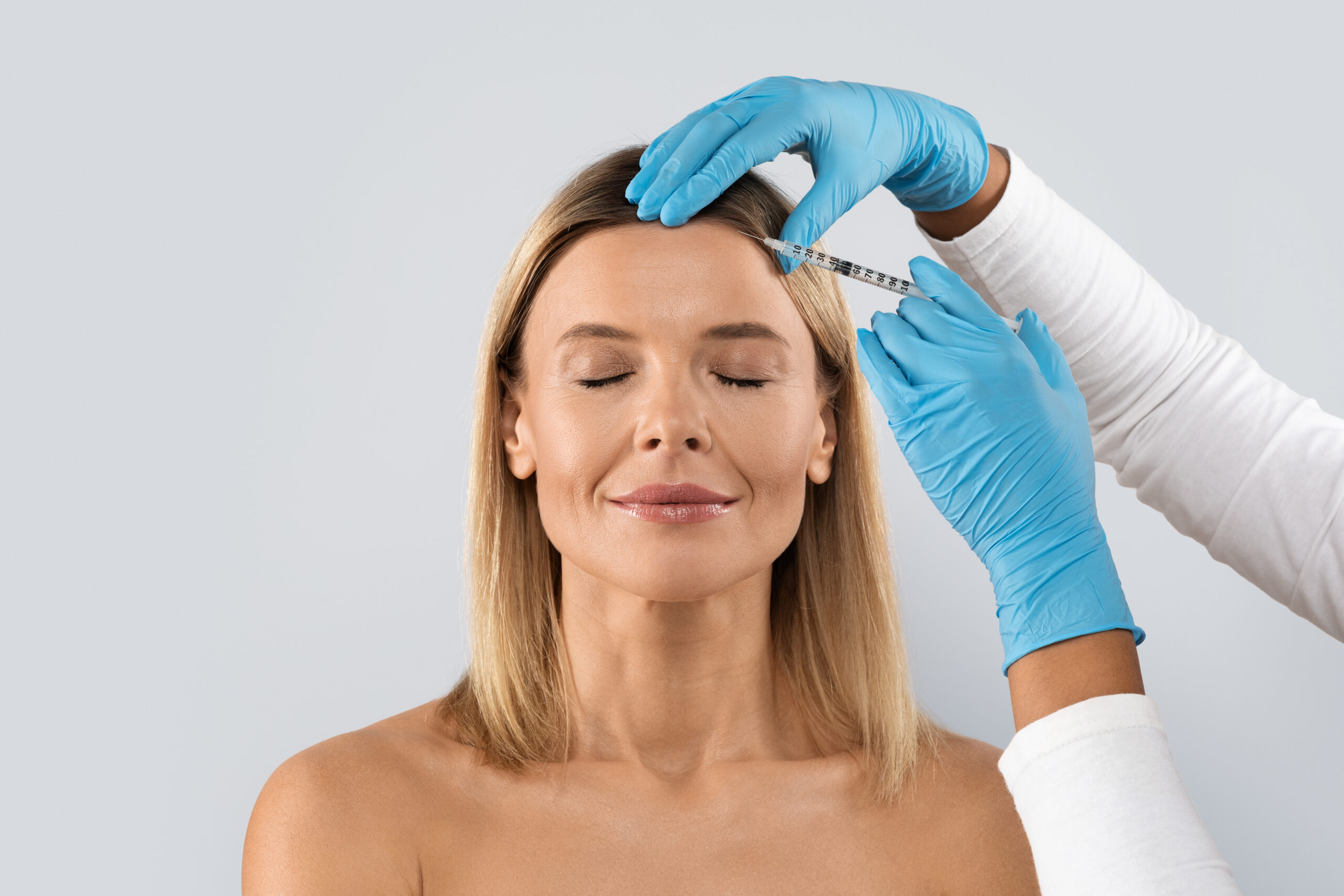 Middle aged woman getting cosmetic injection in her forehead, closeup Body contouring